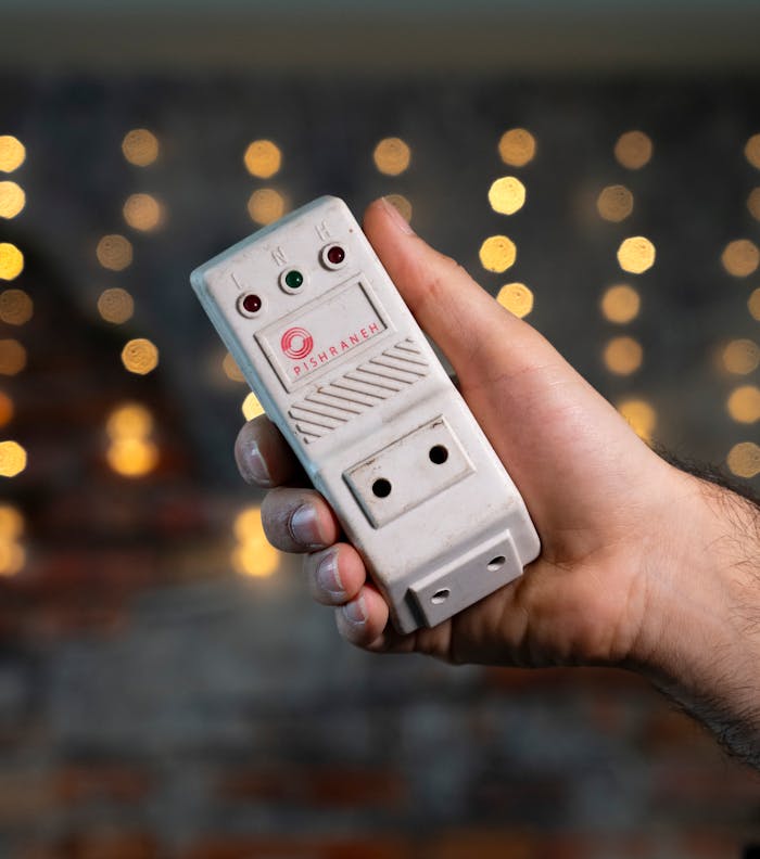 Close-up of a hand holding a surge protector with a bokeh background, emphasizing electronic safety.